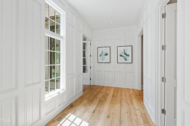 hall featuring ornamental molding and light hardwood / wood-style floors