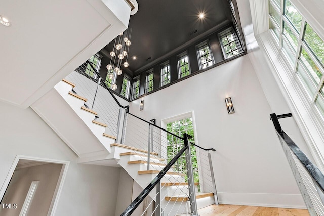 stairs with a towering ceiling and hardwood / wood-style flooring