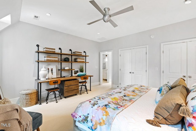 bedroom featuring ceiling fan, light colored carpet, and multiple closets