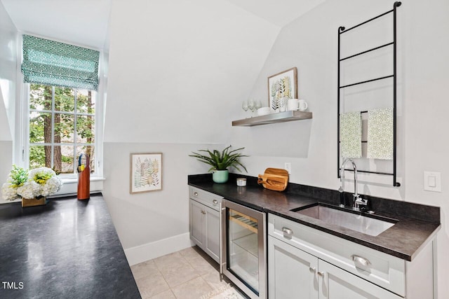 interior space featuring tile patterned floors, lofted ceiling, beverage cooler, and sink