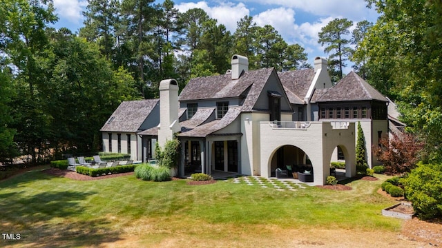 rear view of house featuring a balcony, a yard, and a patio area