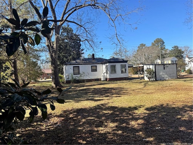 rear view of house with a storage shed and a yard