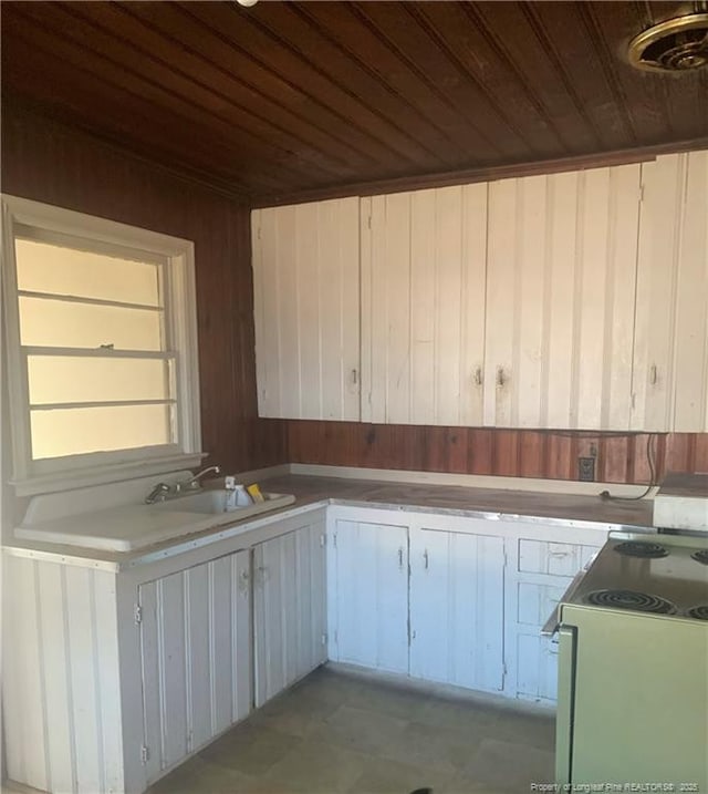 kitchen with electric stove, sink, wood ceiling, and white cabinets