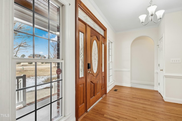 foyer entrance featuring an inviting chandelier, crown molding, and light hardwood / wood-style flooring