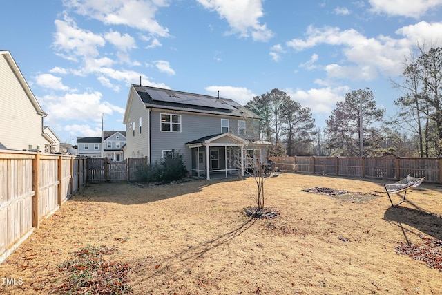 rear view of house with a sunroom and solar panels