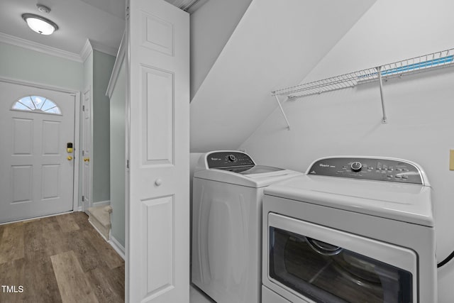 laundry room featuring crown molding, washer and dryer, and light hardwood / wood-style floors