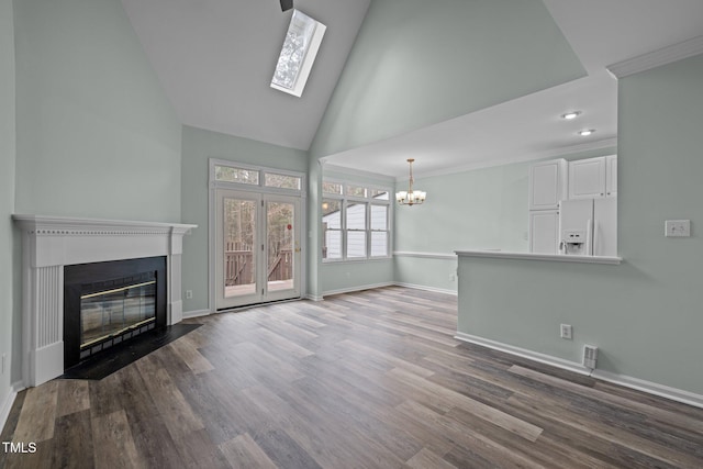 unfurnished living room featuring an inviting chandelier, hardwood / wood-style flooring, a skylight, and high vaulted ceiling