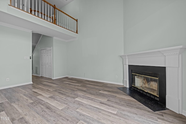 unfurnished living room featuring a high ceiling and light wood-type flooring