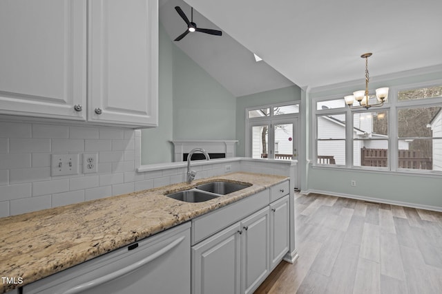 kitchen with sink, dishwasher, backsplash, white cabinets, and vaulted ceiling