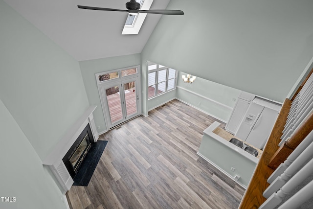 living room with ceiling fan with notable chandelier, high vaulted ceiling, and light hardwood / wood-style floors