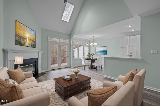 living room with an inviting chandelier, high vaulted ceiling, a skylight, and hardwood / wood-style floors