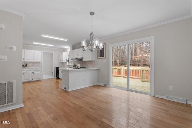 kitchen with tasteful backsplash, white cabinets, ornamental molding, kitchen peninsula, and light wood-type flooring