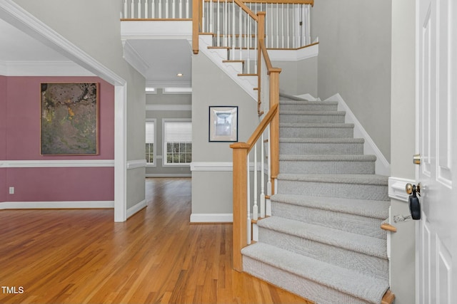 staircase with ornamental molding and wood-type flooring