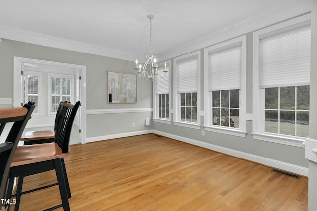 dining room with ornamental molding, a chandelier, and light hardwood / wood-style floors