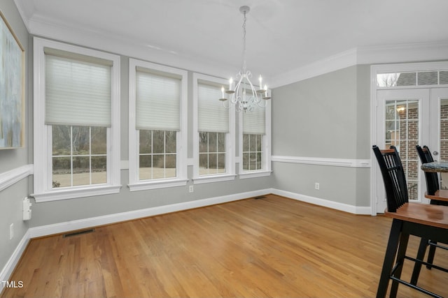 unfurnished dining area featuring ornamental molding, hardwood / wood-style floors, and a notable chandelier