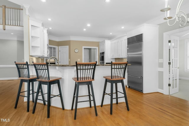 kitchen with white cabinetry, appliances with stainless steel finishes, light hardwood / wood-style flooring, and kitchen peninsula