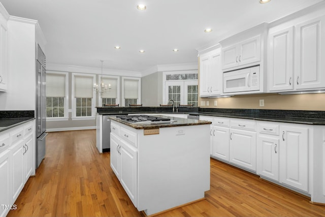 kitchen featuring white cabinetry, stainless steel appliances, decorative light fixtures, and a center island