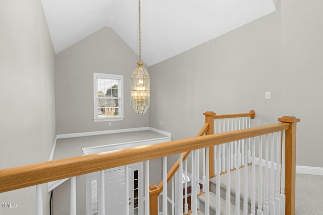 corridor featuring an inviting chandelier, lofted ceiling, and carpet floors