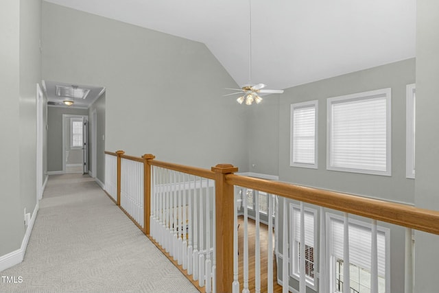 hallway with lofted ceiling, plenty of natural light, and light carpet