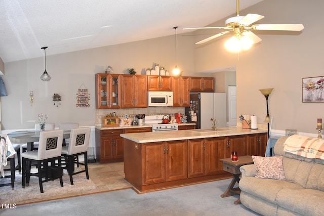 kitchen featuring lofted ceiling, white appliances, backsplash, hanging light fixtures, and kitchen peninsula