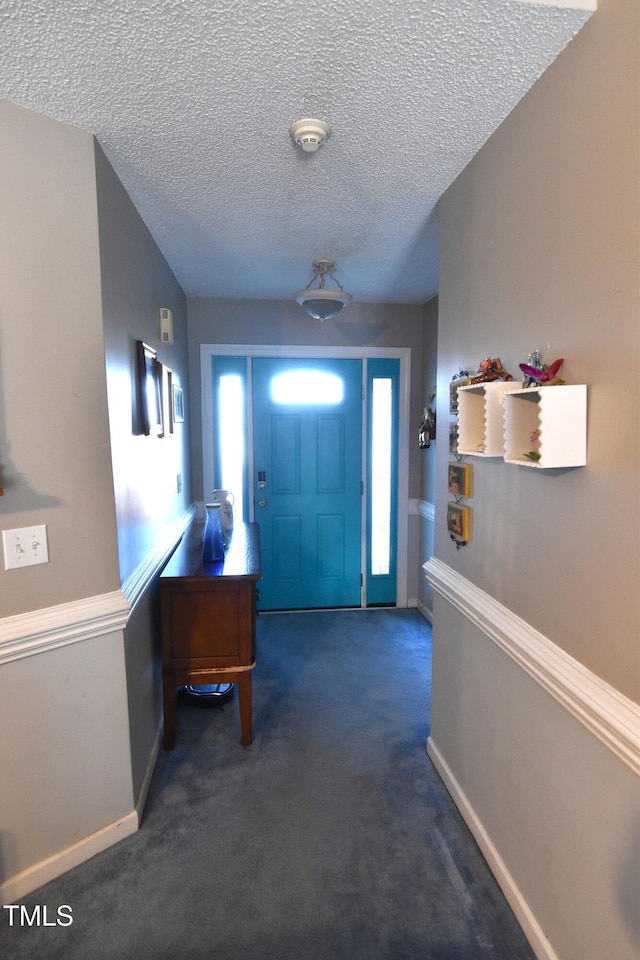 carpeted entryway with a textured ceiling