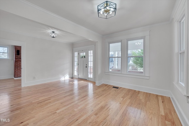 foyer entrance featuring a notable chandelier, ornamental molding, and light wood-type flooring