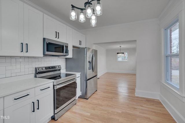 kitchen featuring backsplash, crown molding, stainless steel appliances, and white cabinets