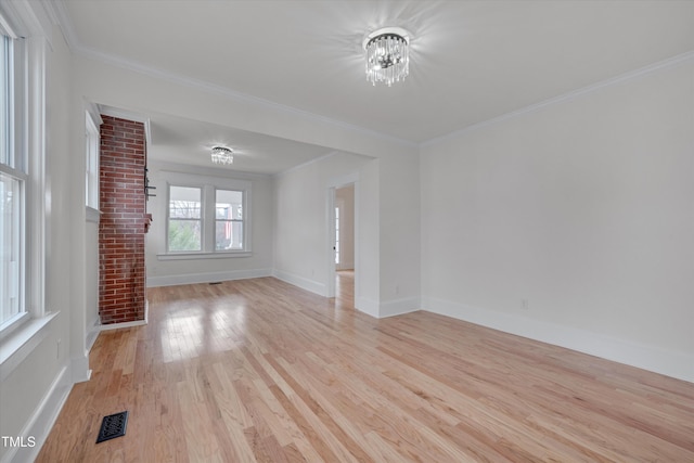 empty room with ornamental molding, light hardwood / wood-style flooring, and a notable chandelier