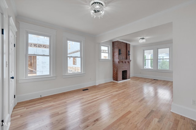 unfurnished living room featuring an inviting chandelier, a fireplace, ornamental molding, and light wood-type flooring