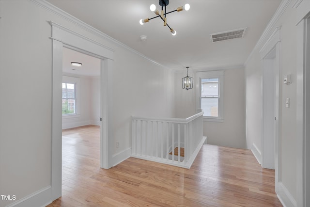 corridor with crown molding, a chandelier, and light hardwood / wood-style flooring