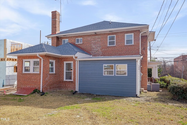 rear view of property featuring a lawn and central air condition unit