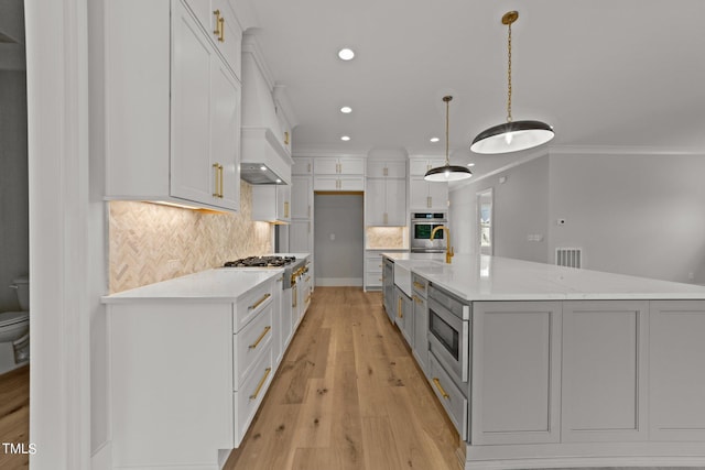 kitchen featuring appliances with stainless steel finishes, pendant lighting, white cabinets, and decorative backsplash