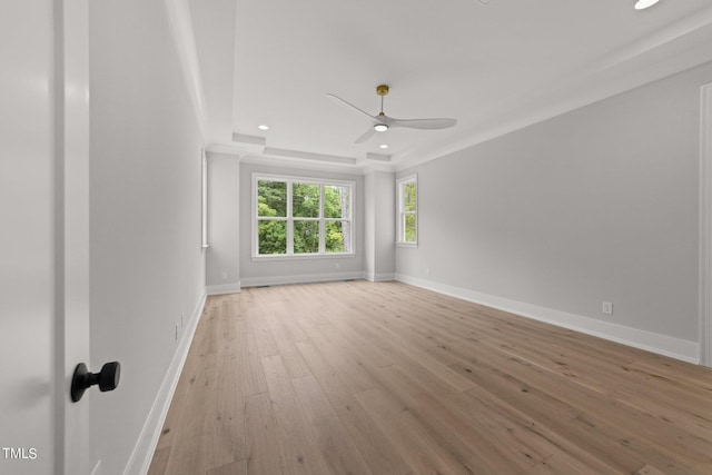 spare room with crown molding, a tray ceiling, light hardwood / wood-style floors, and ceiling fan