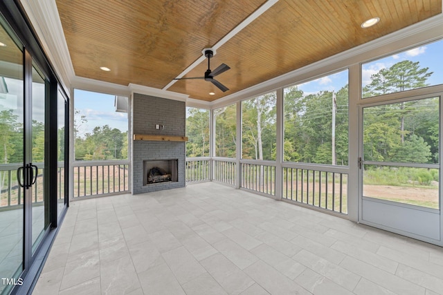 unfurnished sunroom featuring plenty of natural light, wooden ceiling, and ceiling fan