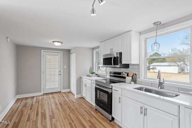 kitchen with pendant lighting, sink, white cabinetry, stainless steel appliances, and decorative backsplash