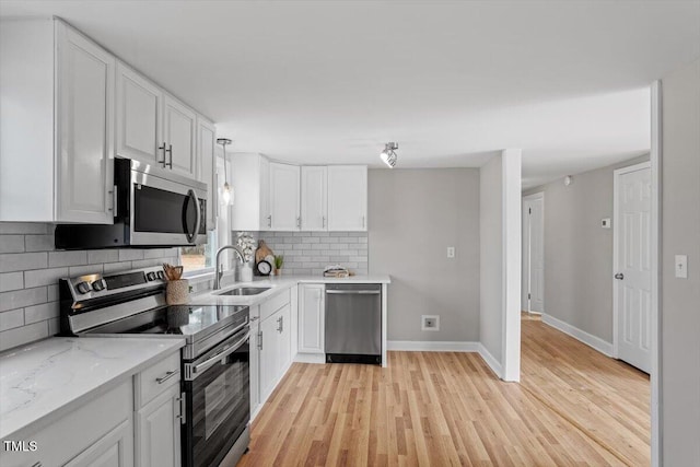 kitchen with white cabinetry, sink, hanging light fixtures, and appliances with stainless steel finishes