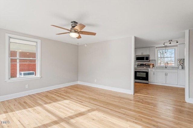 empty room with sink, light hardwood / wood-style flooring, and ceiling fan