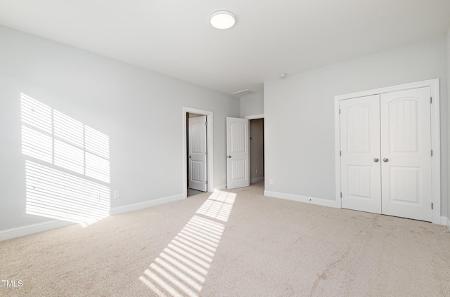 unfurnished bedroom featuring light colored carpet and a closet