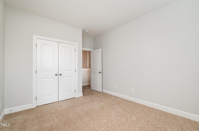 unfurnished bedroom with light carpet and a closet