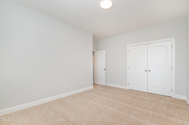 unfurnished bedroom featuring light colored carpet and a closet