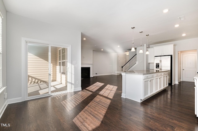 kitchen featuring pendant lighting, light stone counters, white cabinetry, and a kitchen island