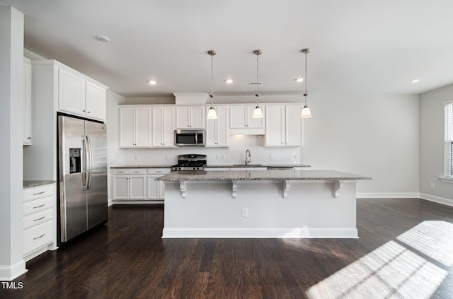 kitchen with white cabinetry, stainless steel appliances, and an island with sink