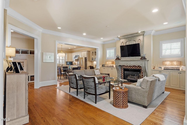 living room with crown molding, a large fireplace, and light wood-type flooring