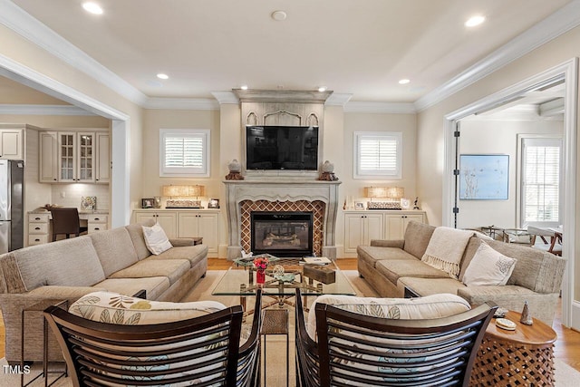 living room featuring crown molding, a fireplace, and light wood-type flooring