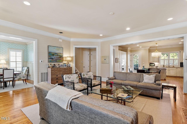 living room featuring crown molding, plenty of natural light, and light wood-type flooring