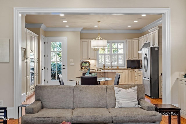 living room with crown molding, sink, and light hardwood / wood-style flooring