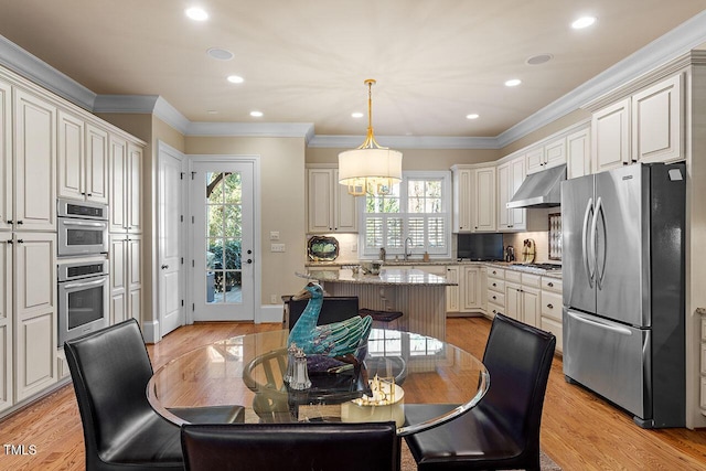 kitchen with decorative light fixtures, light hardwood / wood-style flooring, a kitchen island, stainless steel appliances, and light stone countertops