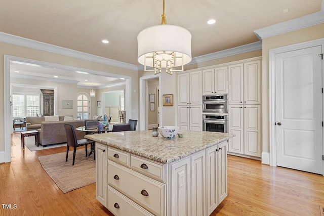 kitchen with pendant lighting, a center island, stainless steel double oven, an inviting chandelier, and light hardwood / wood-style flooring