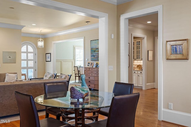 dining area with ornamental molding and light wood-type flooring