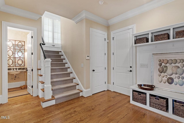 mudroom with ornamental molding and light hardwood / wood-style floors